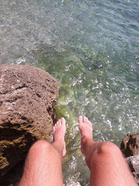 Low section of feet on rock in sea