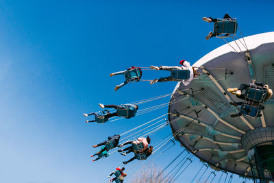 Low angle view of people enjoying chain swing ride at amusement park