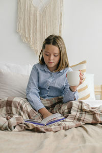 Portrait of young woman sitting on bed at home