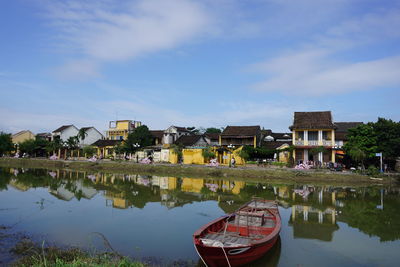 Lake by houses in town against sky