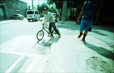 Rear view of man riding bicycle on city street