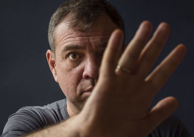 Close-up portrait of man with hand against black background