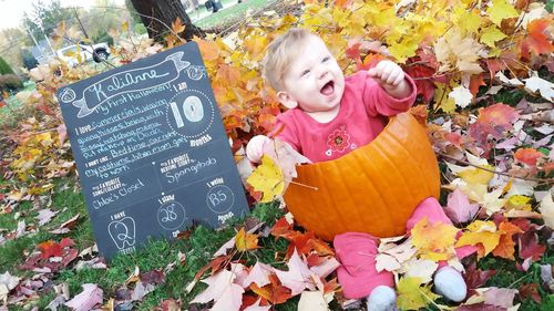 Full length of smiling boy with flowers in park during autumn