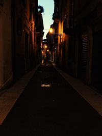 Empty alley amidst buildings in city at night