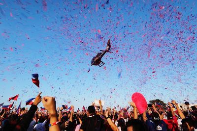 People with confetti falling from helicopter during festival