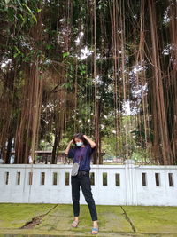 Full length of woman standing against trees