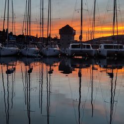 Boats moored in sea against sky during sunset