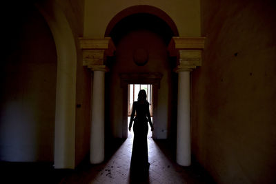 Rear view of woman standing in corridor of building