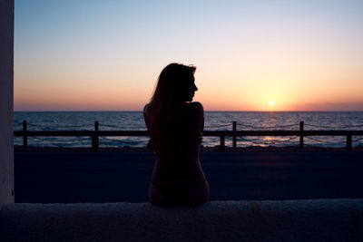 A young girl watching the sunset by the sea. holiday concept