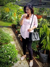 Full length of woman standing by potted plants