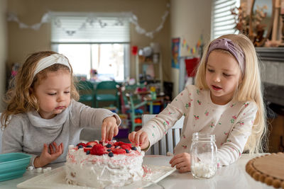 Cute girls eating birthday cake at home