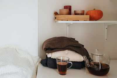 A stack of autumn sweaters next to warm tea and candles. autumn mood