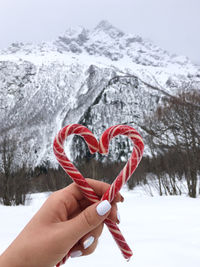 Midsection of person holding heart shape in snow