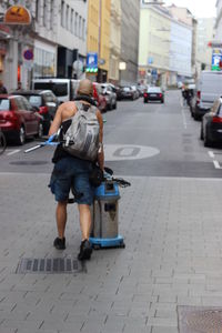 Rear view of man walking on street in city