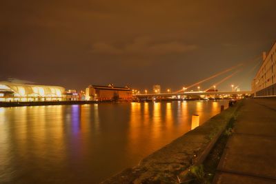 Illuminated bridge over river against sky at night