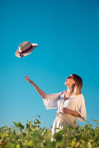 Woman with umbrella on field against blue sky