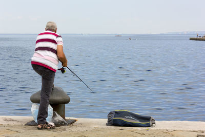 Rear view of woman on beach against sky