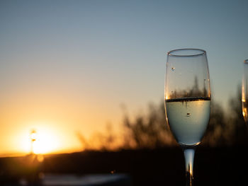 Close-up of wineglass against sky during sunset