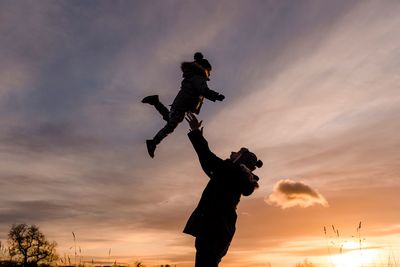 Low angle view of silhouette man jumping against sky during sunset