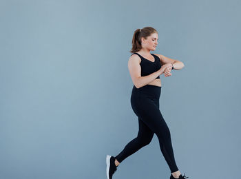 Low angle view of woman exercising against gray background