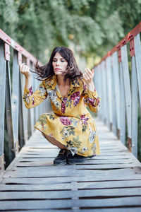 Young woman crouching on footbridge