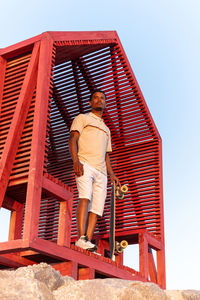 Low angle view of man standing on roof against clear sky