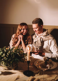 A man and a woman in love at a romantic dinner give each other gifts for christmas in the evening