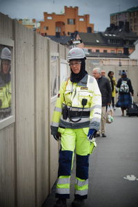 Full length of female firefighter in uniform standing by wooden room