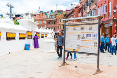 People walking on street amidst buildings in city