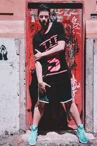 Full length portrait of young man standing against wall