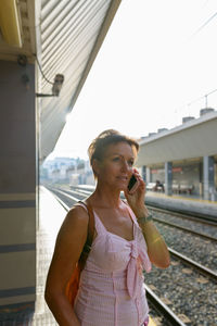 Woman talking on phone at railroad station