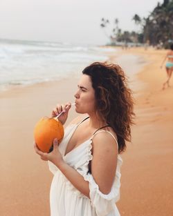 Woman holding ice cream while standing on beach