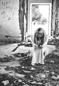 Woman with head in hands crouching in abandoned house