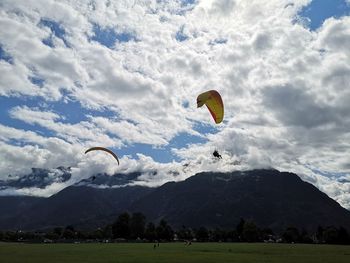 Person paragliding over mountains against sky