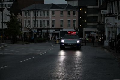 Cars on city street by buildings at night