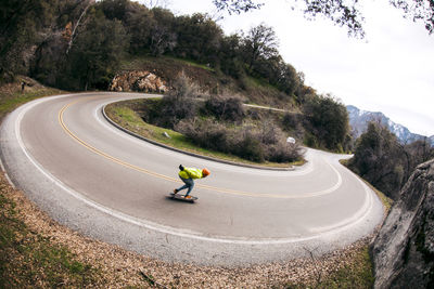 High angle view of man skateboarding on hairpin curve road against sky