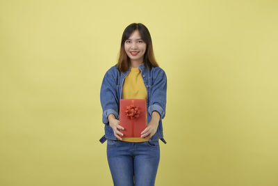 Portrait of a smiling young woman against yellow background