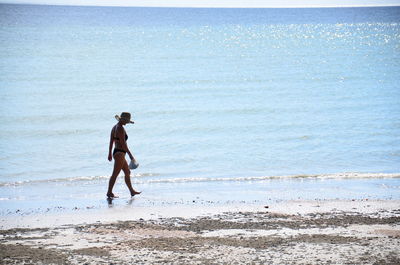 Side view of woman wearing bikini walking at beach