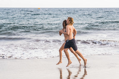 Full length of couple running at beach