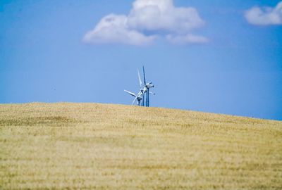 Wind turbines in field against sky