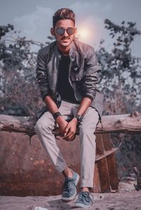 Full length of young man wearing sunglasses standing against trees