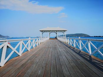 Wooden footbridge on pier against sky