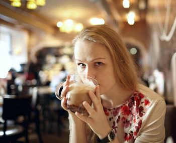 Portrait of beautiful woman drinking cappuccino in cafe
