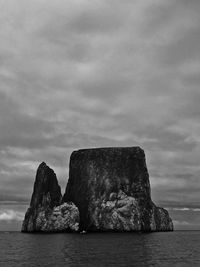 Rock formation by sea against sky