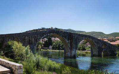 Arch bridge over river against clear blue sky