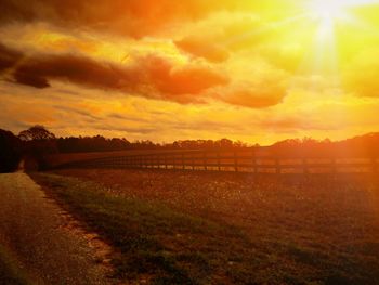 Scenic view of landscape against cloudy sky at sunset