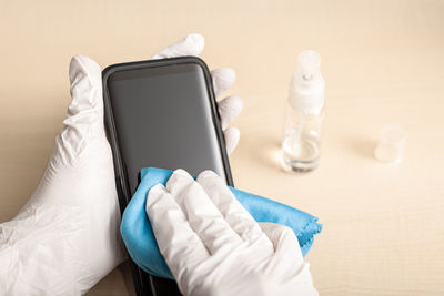 Close-up of hand holding mobile phone on table