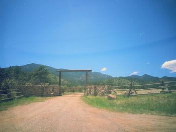 Road leading towards mountains against clear blue sky