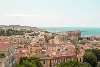 Aerial view of townscape by sea against sky