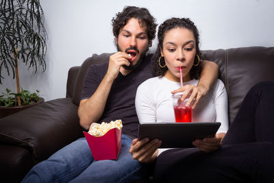 Close-up of couple using digital tablet while sitting on sofa at home